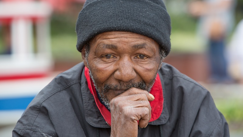 Um homem negro e idoso de touca e casaco, olhando para a foto. Imagem para ilustrar a matéria sobre o Dia da Consciência Negra.